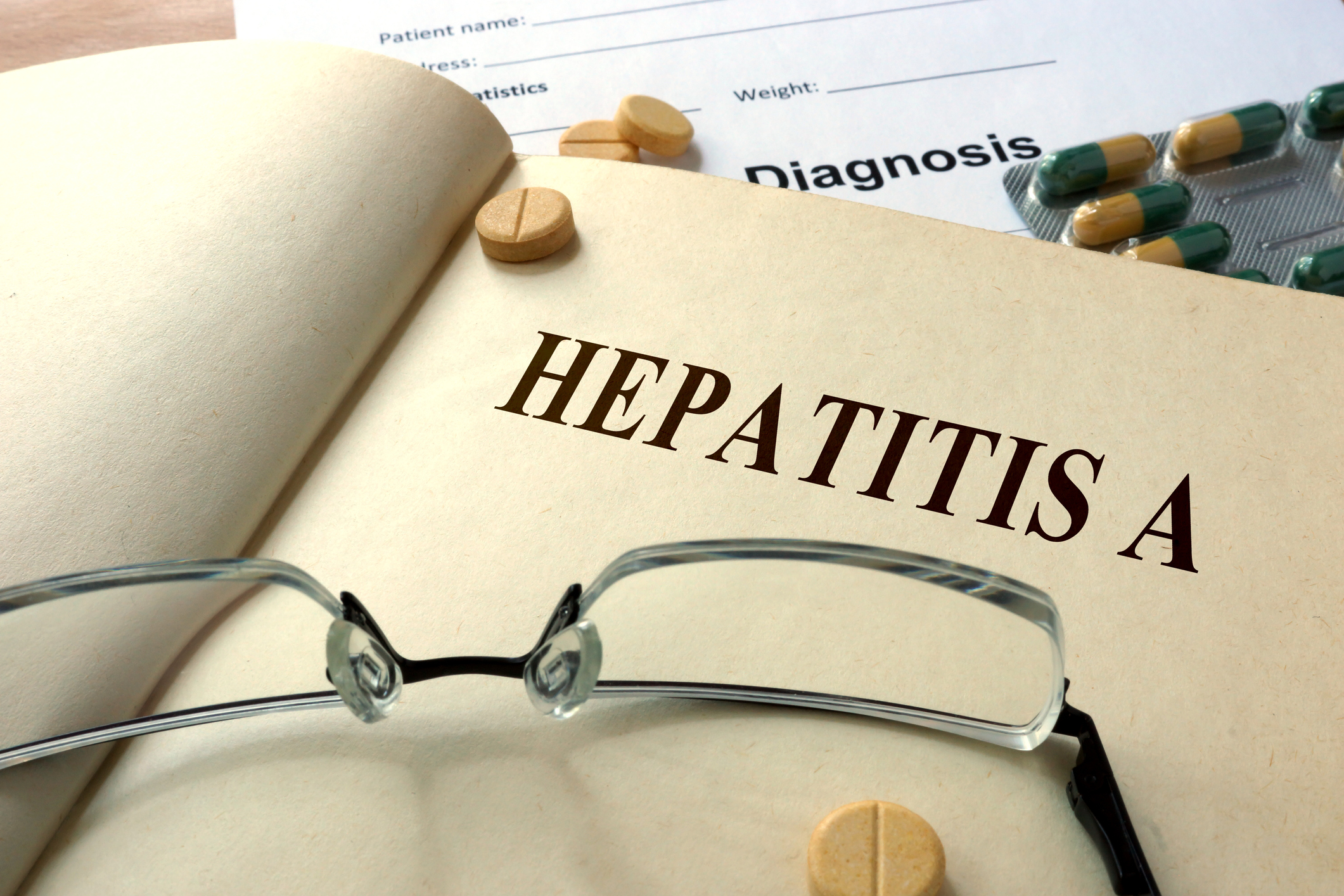 Word Hepatitis A  on a paper and pills on the wooden table.